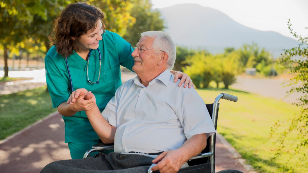 Caregiver assisting an elderly veteran in a wheelchair outdoors in North Carolina