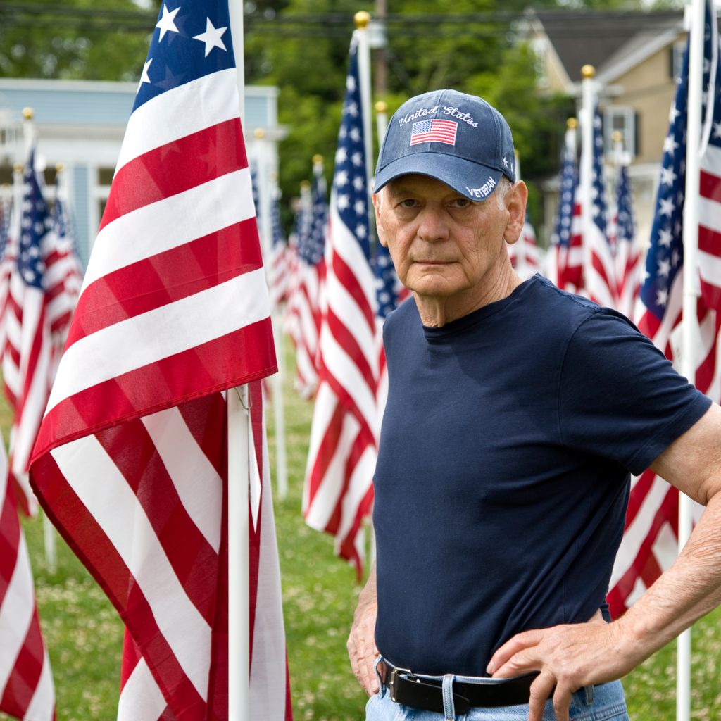 Older veteran among American flags representing Aid and Attendance income eligibility