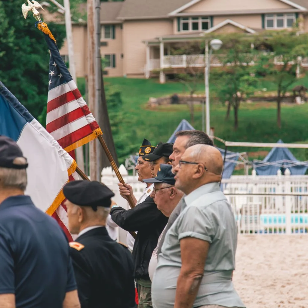 Veterans and flag bearers gathered at an outdoor ceremony.