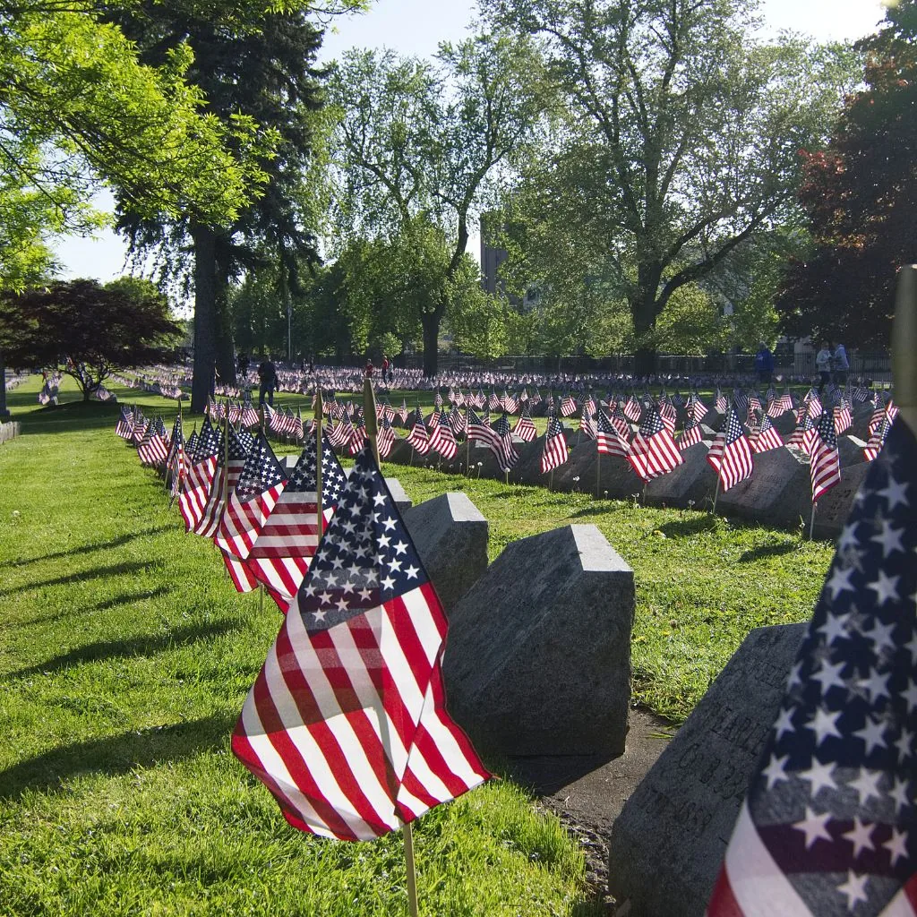 Small American flags placed in grass at a memorial display.