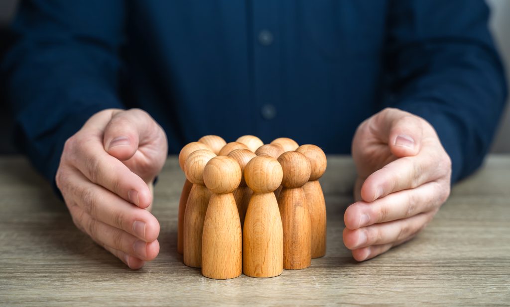 Hands protecting wooden figures representing veterans and their families